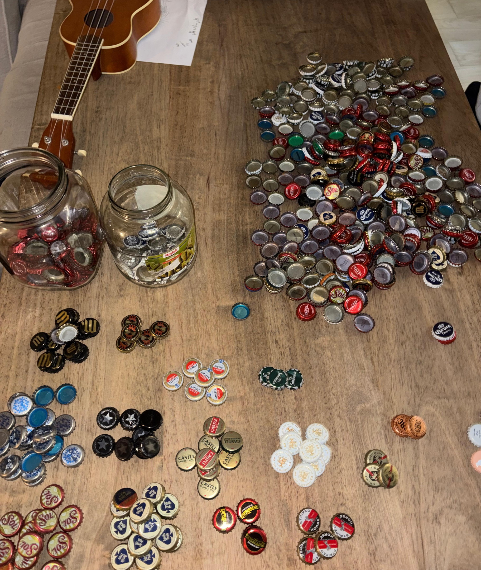 Bottle tops sorted by colour and brand, ready to be pressed into playing pieces.