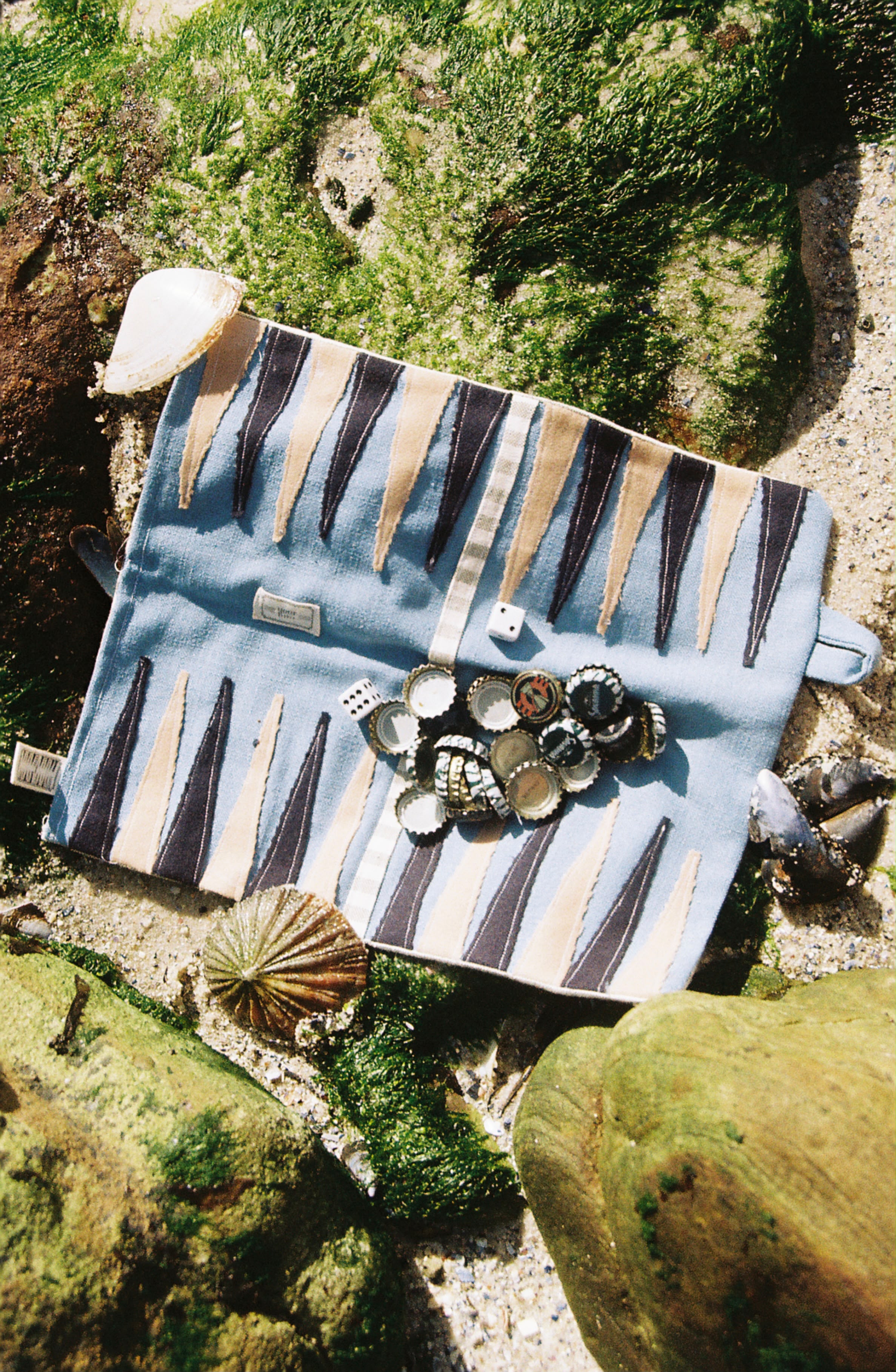 A YourTurn board on the rocks with its recycled bottle-cap pieces and shells.