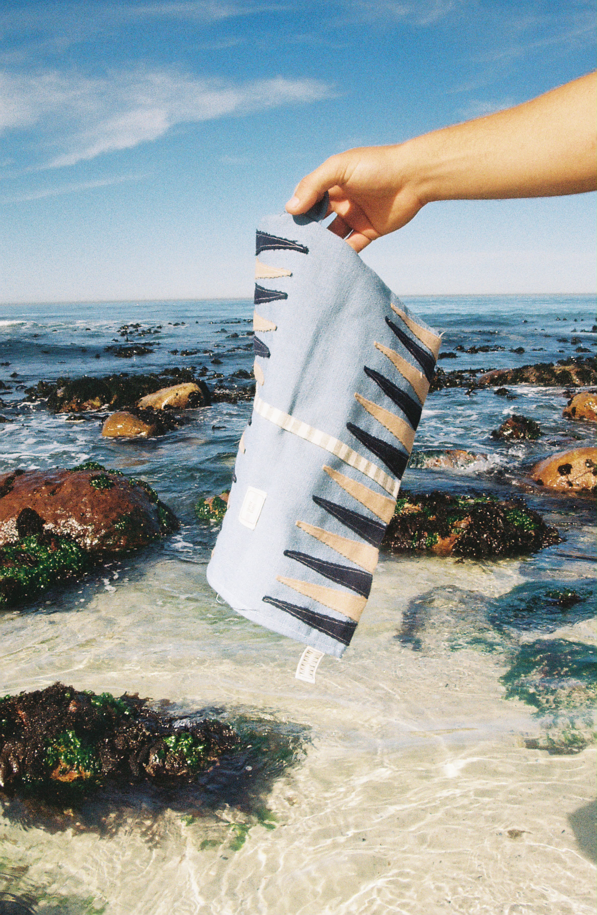 Holding a YourTurn board up over the tidal rocks.